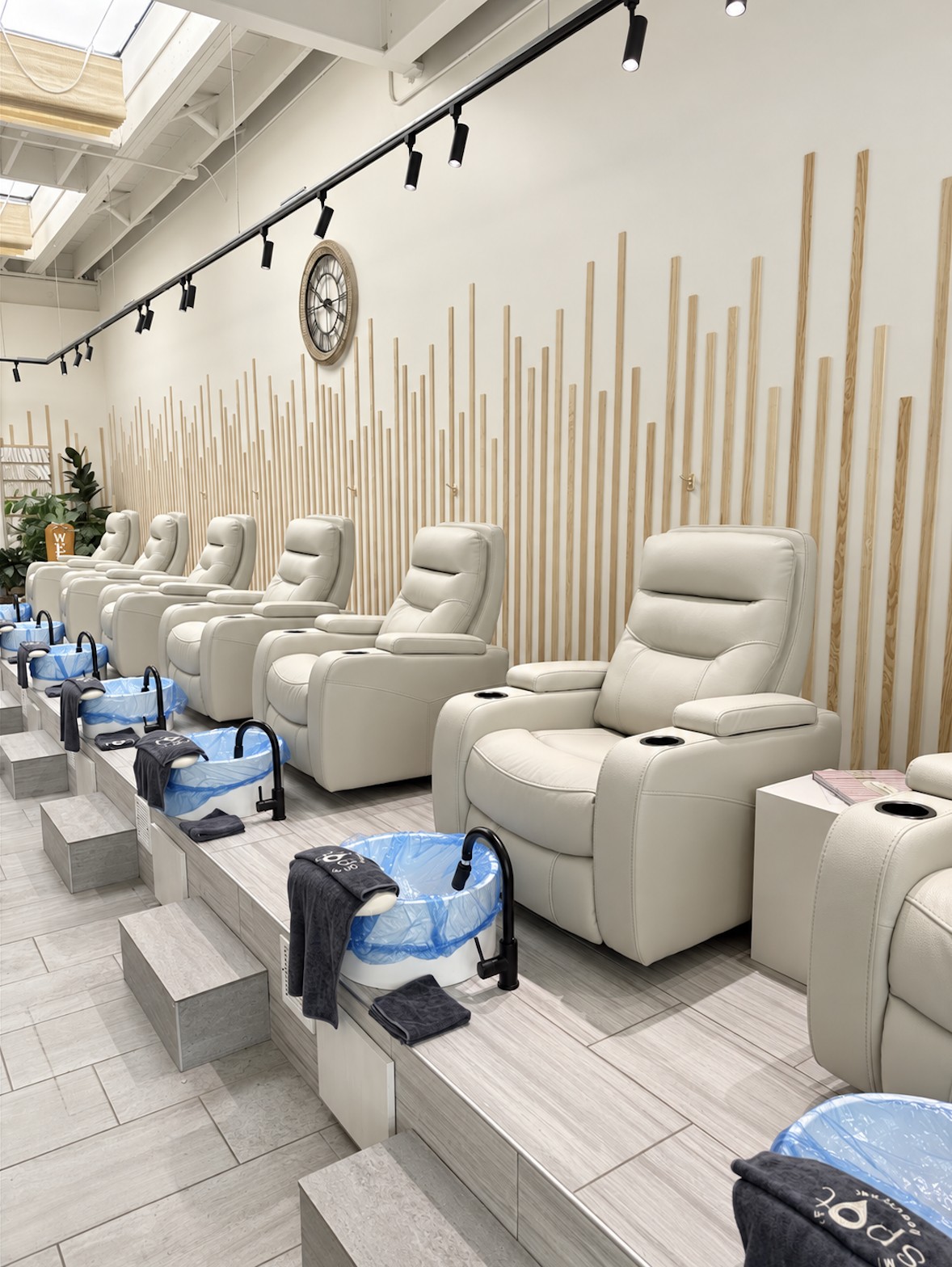 Row of pedicure chairs beside the salon's wood slat feature wall