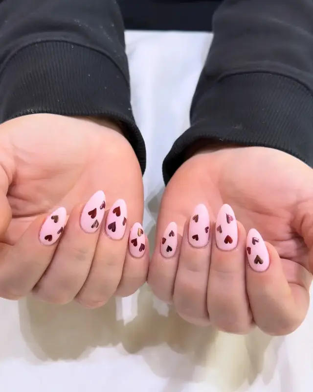Pink heart nail art displayed in two hands